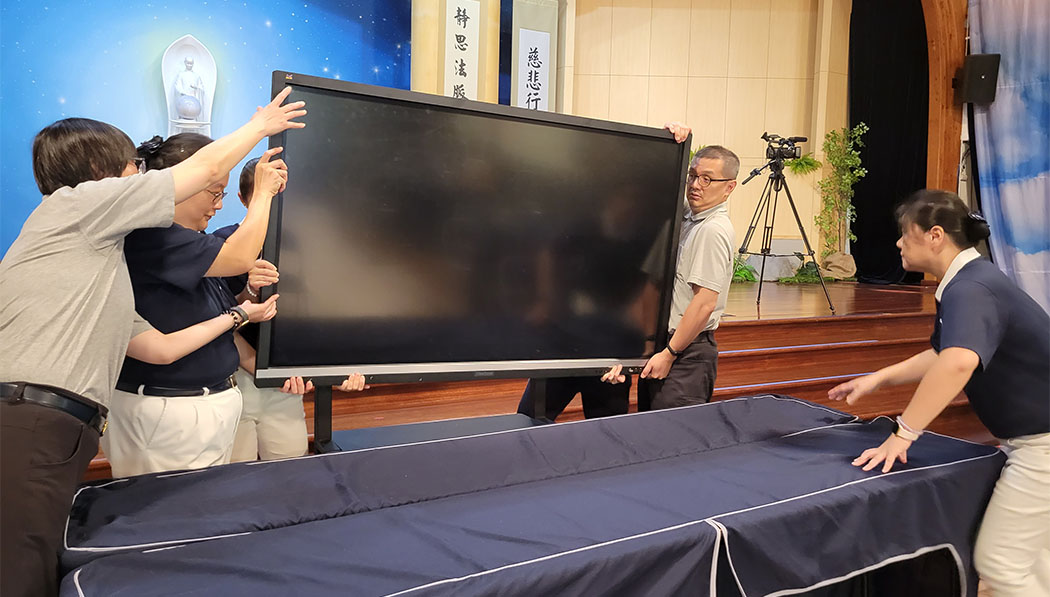 Volunteers putting big TV screen on the table