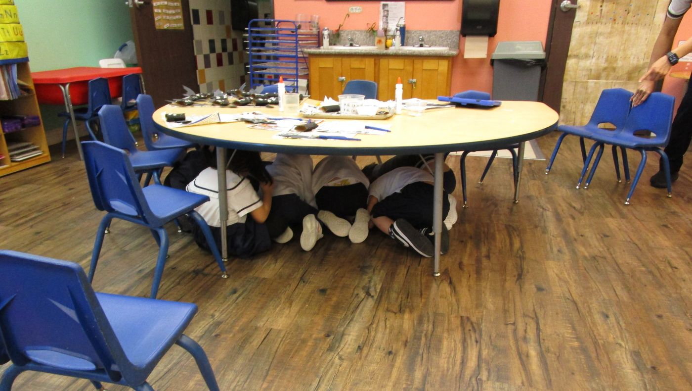 警報響起後，學生馬上就地躲到一張大圓桌底下。攝影／Judy Anderson