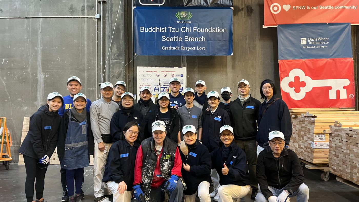 Tzu Chi and Hope Factory volunteers take a photo under the banner identifying the Tzu Chi Seattle Branch as a tiny home donor. Photo/Xinqian Zheng