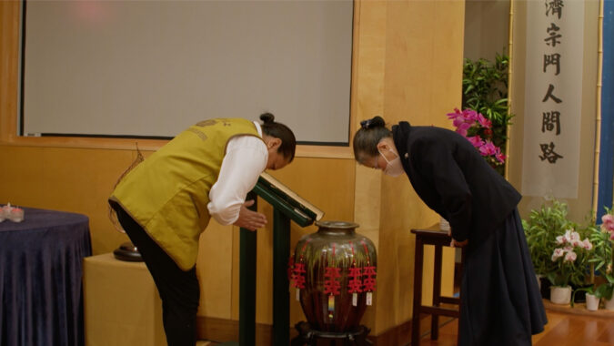 Tzu Chi training volunteer and volunteer bow to each other