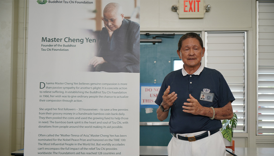 Volunteer introducing Tzu Chi in front of a poster