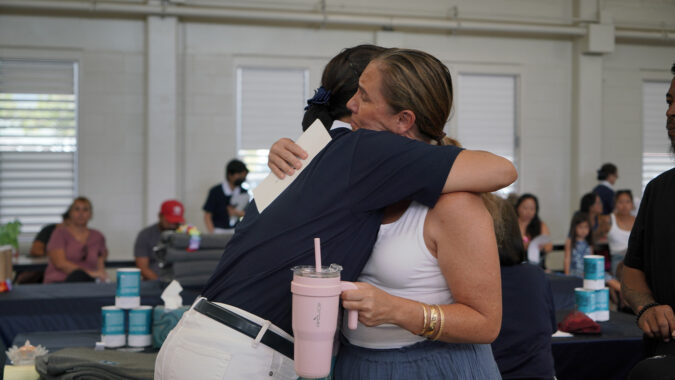 volunteer and Maui fire survivor embracing each other