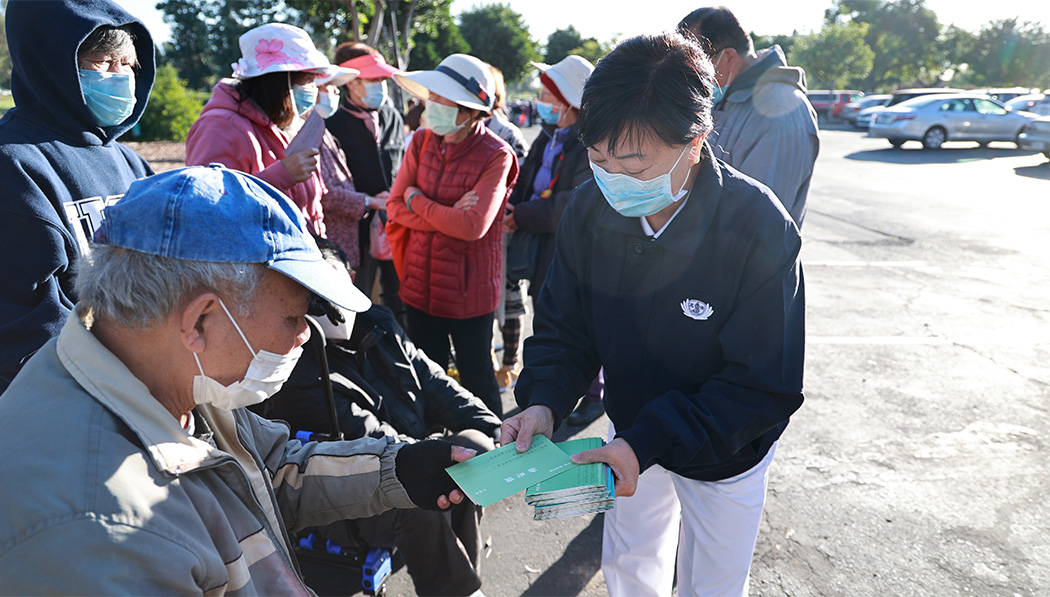 Volunteer distributes Jing Si Aphorisms books to waiting people