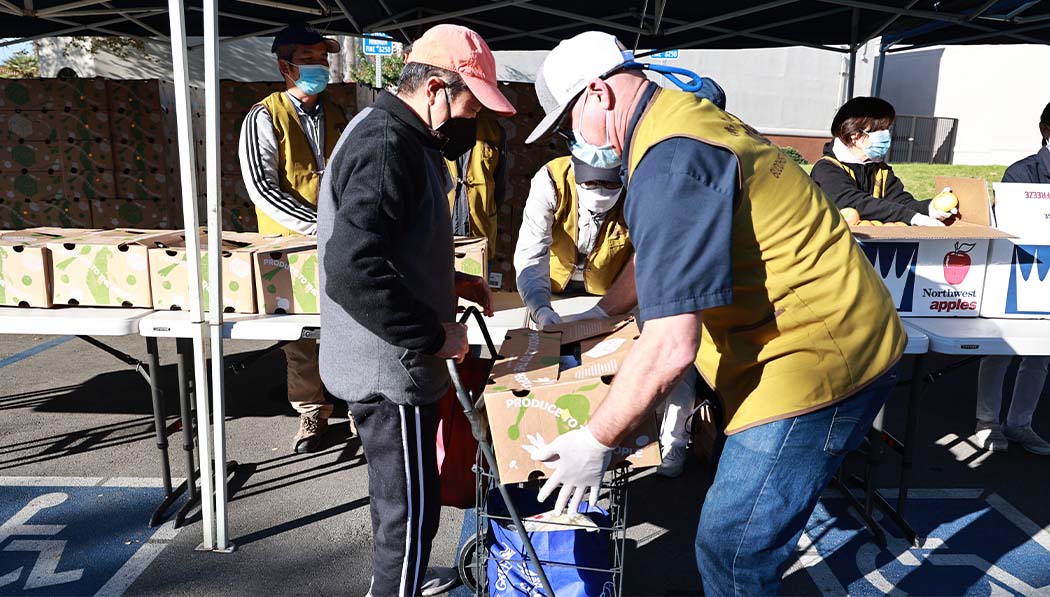Volunteers carefully place food in people’s shopping carts