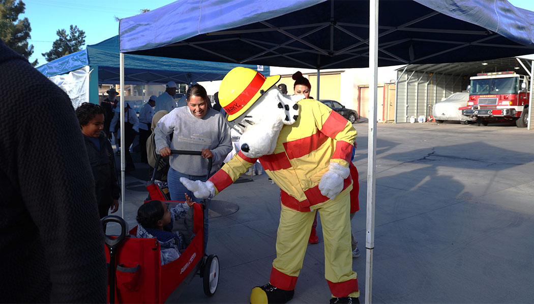 Kid interacting with cartoon dog wearing a firefighter uniform