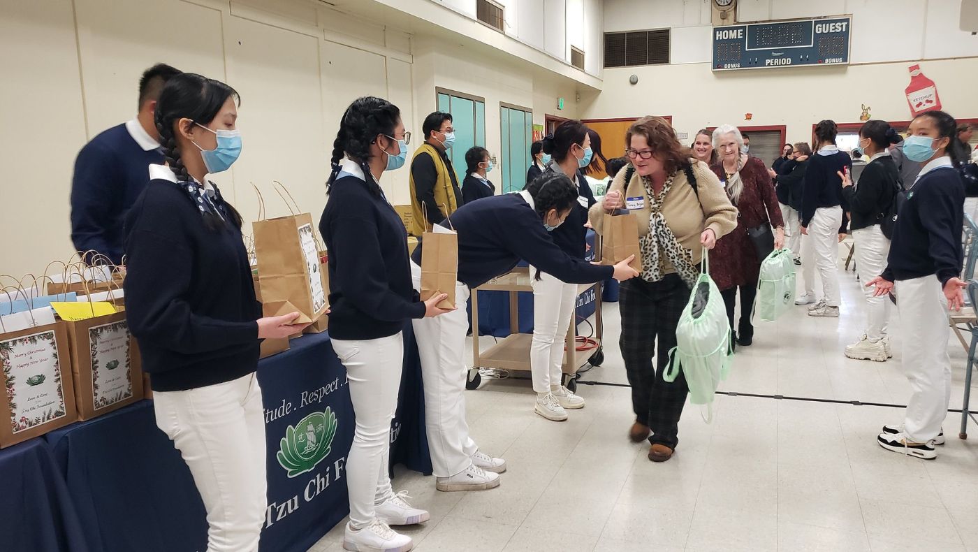 Before leaving the celebration, energetic Sacramento Tzu Shao and volunteer parents respectfully bow and present Christmas gift bags and blankets. Photo/CM Yung