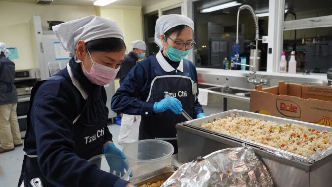 Volunteers bring cooked hot food to the kitchen of the shelter to prepare for distribution.