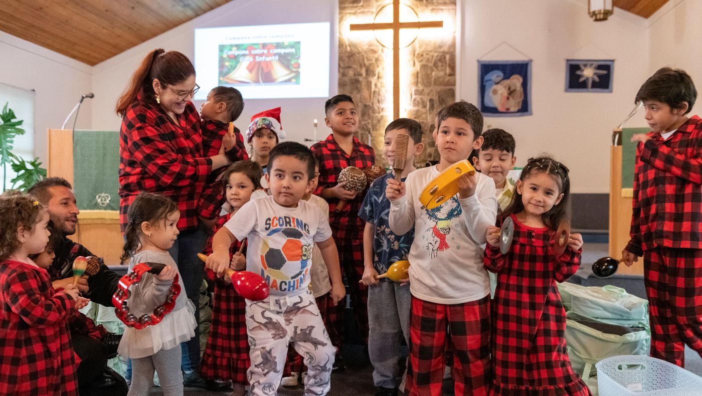 Children hold rattles and perform Christmas songs and dances.
