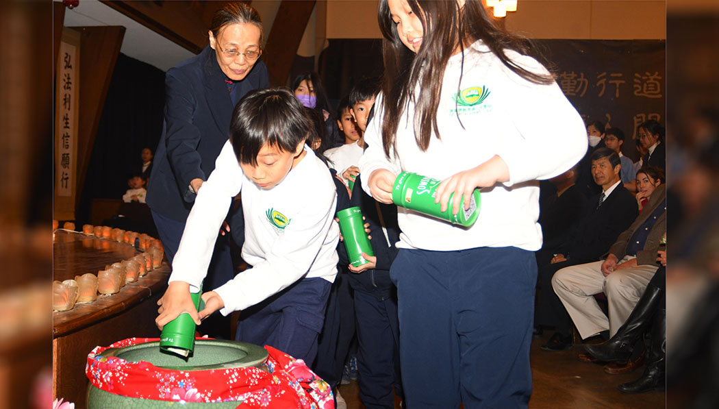 Tzu Chi Academy students pour donations from the Bamboo Banks into the merit pool