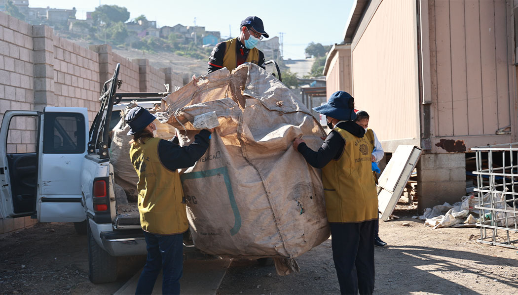 Voluntarios de Tzu Chi empacan los materiales reciclables previamente recolectados en grandes bolsas tejidas y los llevan a la estación de reciclaje. Foto/Shuli Lo
