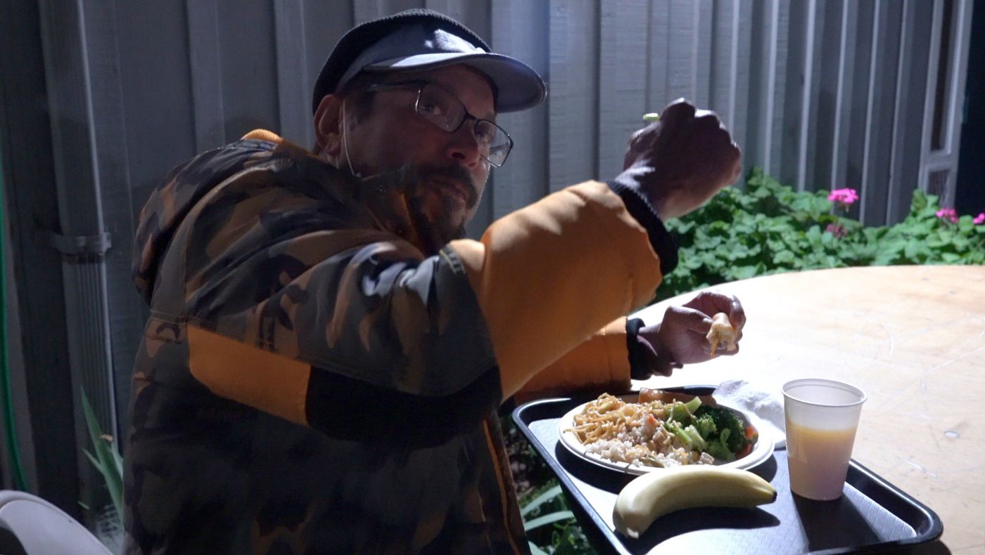 Las personas sin hogar disfrutan felizmente su cena. Foto/Renee Liu