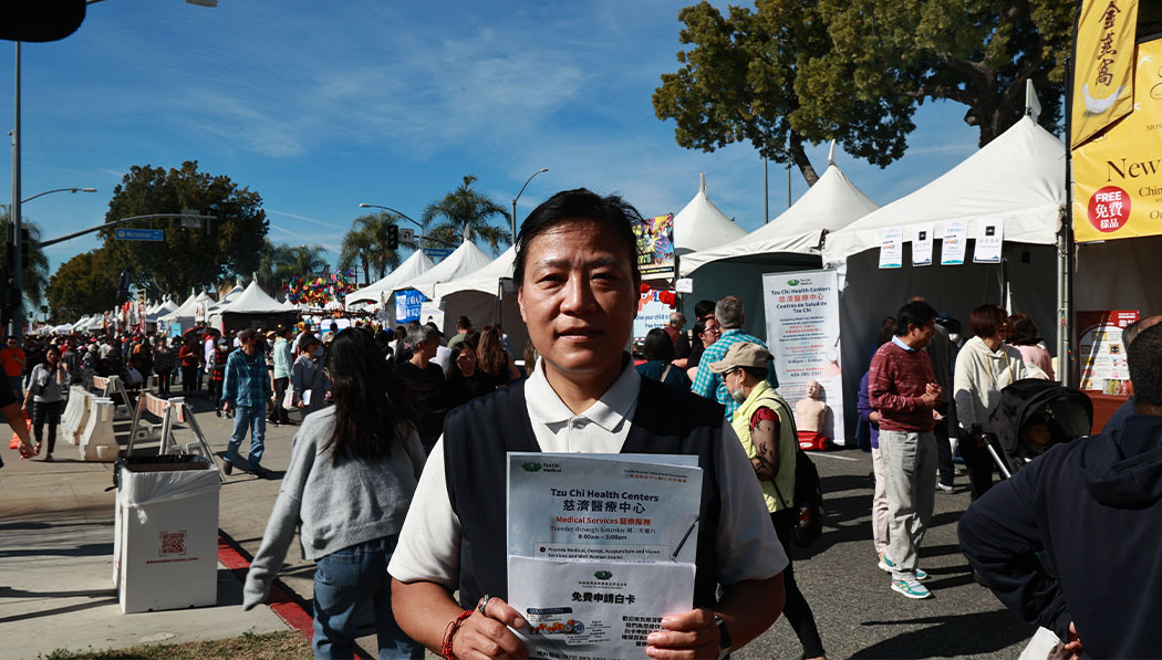 Tzu Chi volunteer holding MediCal promotion flyer