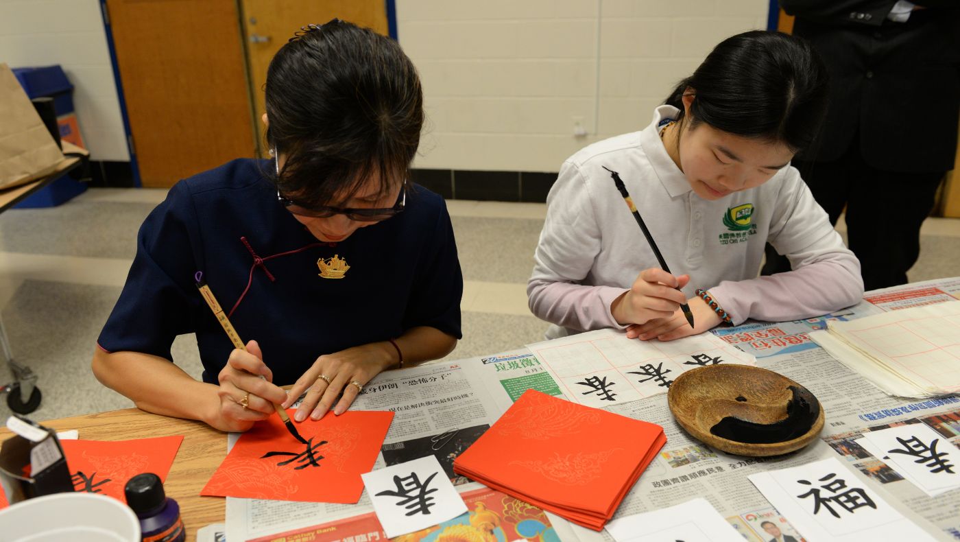 Tzu Chi volunteers and students use calligraphy brushes to write the Chinese character "spring" together.