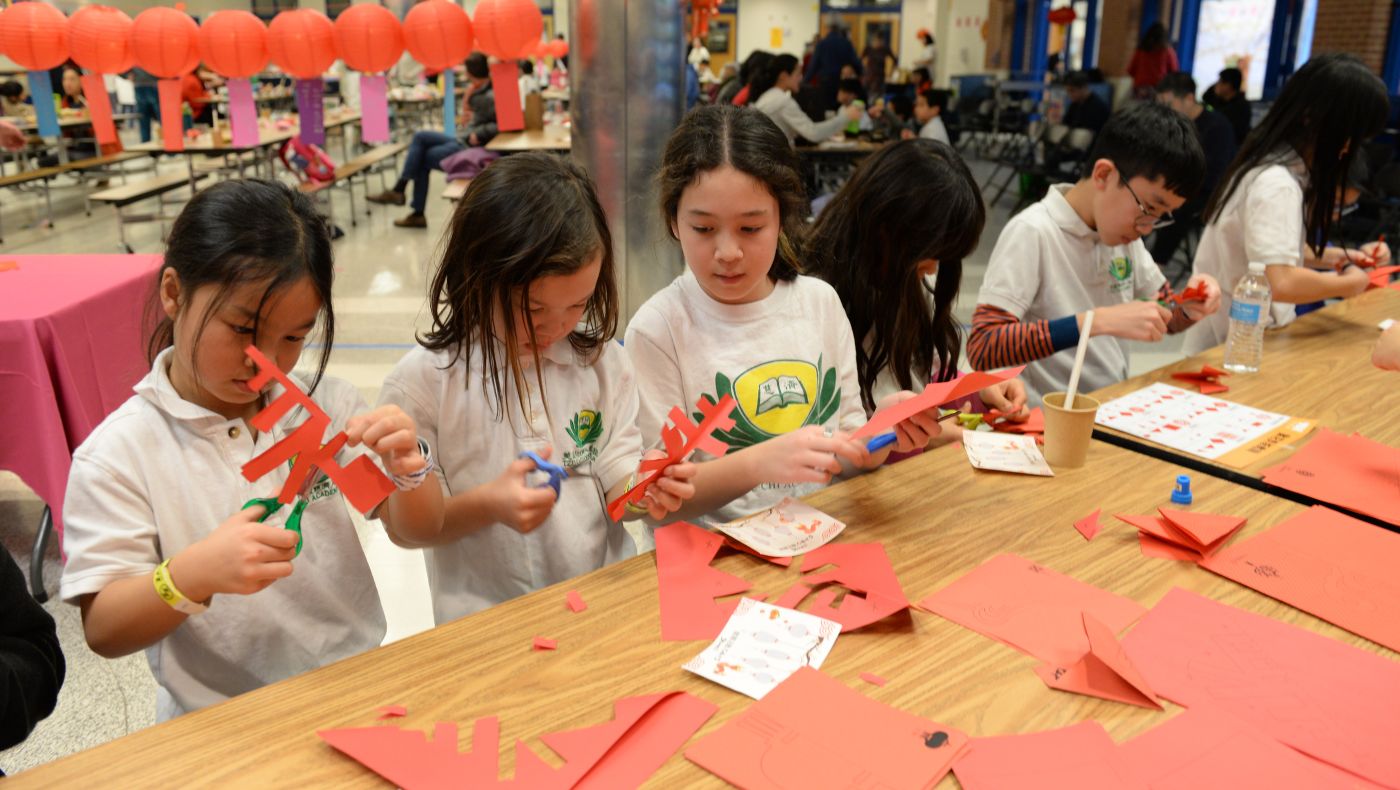 Students of the Humanities School use scissors and red paper to cut out the word "spring".