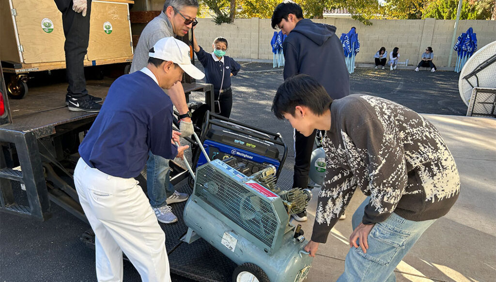 Chicos de la secundaria de TSMC ayudan a cargar generadores y compresores de aire en los camiones.  Foto/Oficina Nacional de Tzu Chi