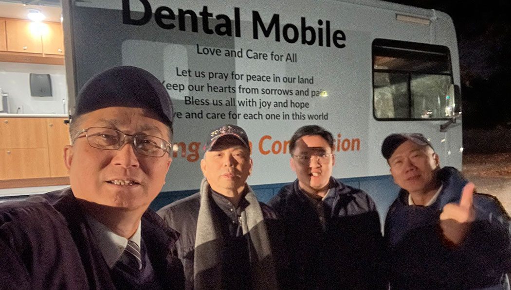Cuatro voluntarios de Tzu Chi posan frente a la clínica móvil dental móvil. Foto/Pinhao Qiu