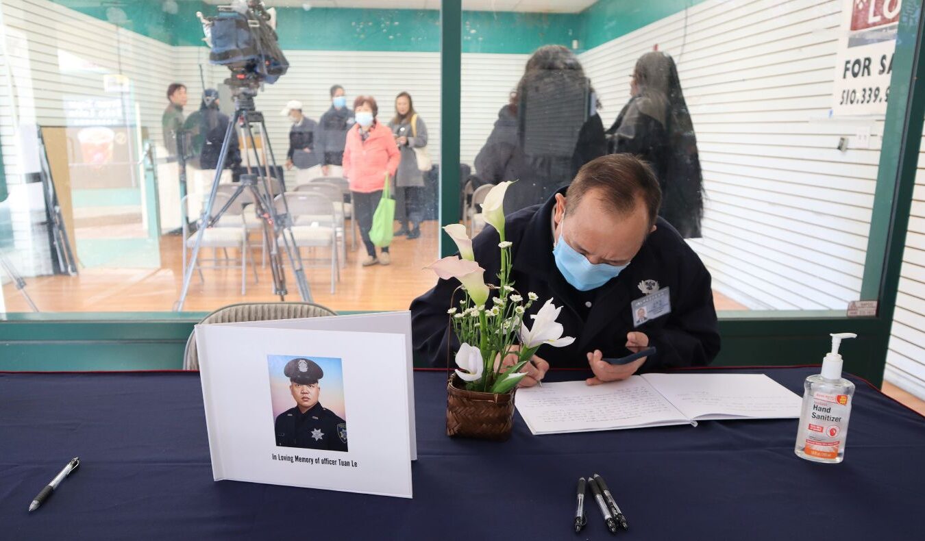 A fellow officer signs Officer Tuan Le’s memorial book. Photo/ Annita Xu