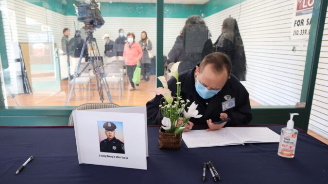 A fellow officer signs Officer Tuan Le’s memorial book. Photo/ Annita Xu