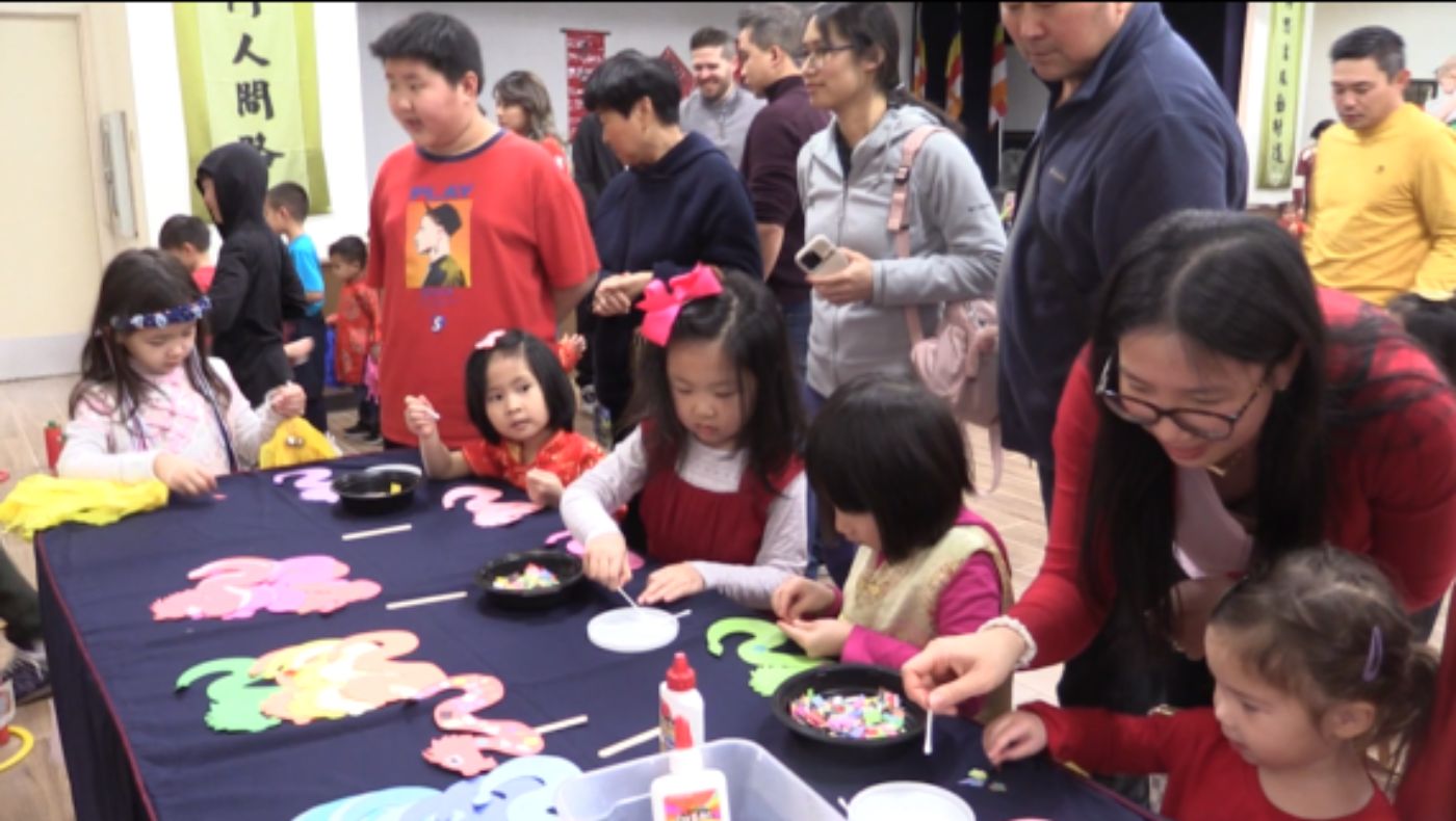 Parents watch children making dragon stickers by hand.