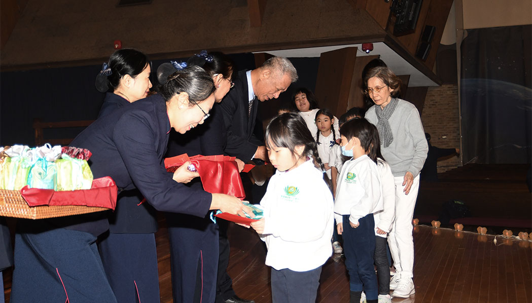 El director ejecutivo de la región central, Yuanliang Ling, entrega paquetes rojos a los estudiantes de la Academia Tzu Chi. Foto/Xixiong Li