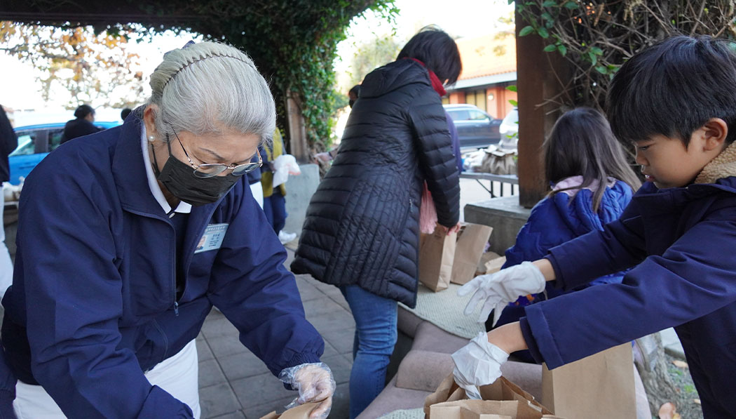 Adultos y niños trabajan juntos para empacar y distribuir desayunos calientes. Foto/Renee Liu