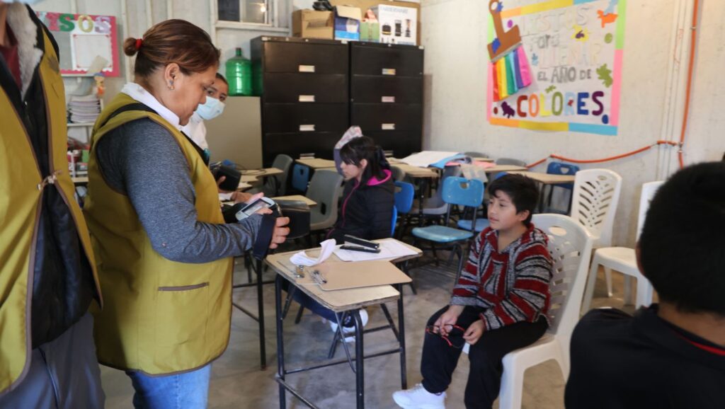 Volunteers use instruments to screen children's eyesight.