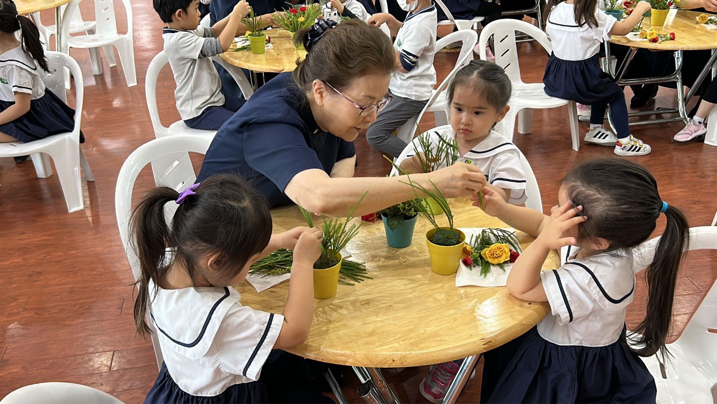 Flower arrangement volunteers instruct children on how to make flowers present the truth, goodness and beauty in different appearances.