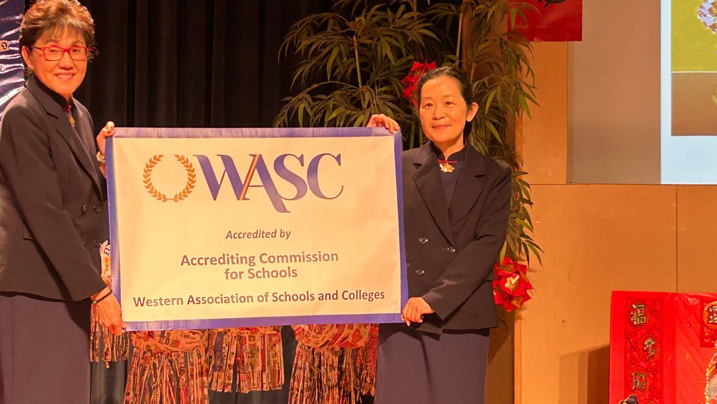 Li Qiongxun (right), CEO of the Tzu Chi American Education Foundation, conducts a flag-presenting ceremony for Tzu Chi American Humanities School’s WASC accreditation to principal Zuo Shaoling.