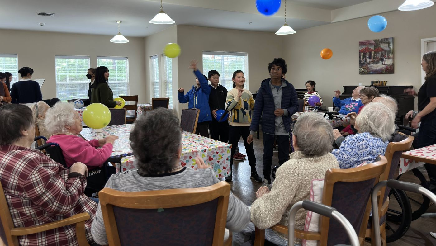 Young students happily play balloon sports with the elderly.