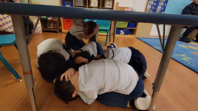 Students from Tzu Chi’s Great Love Kindergarten demonstrate how to immediately seek emergency shelter when an earthquake strikes, hide under their desks, and protect their heads with their hands.