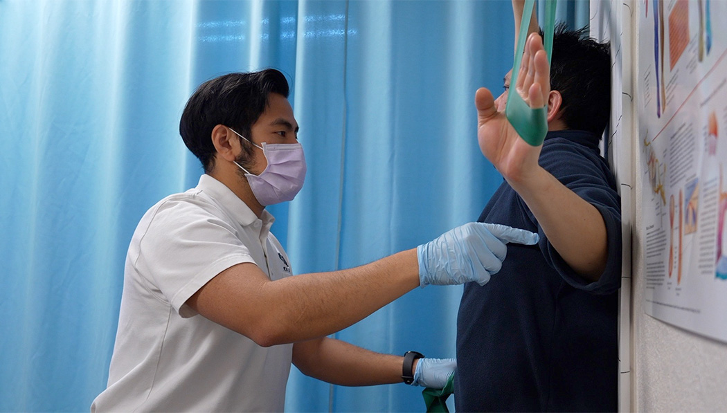 Dr. Benjamin Su instructs patient Wilson Chan to use elastic bands to do exercises.