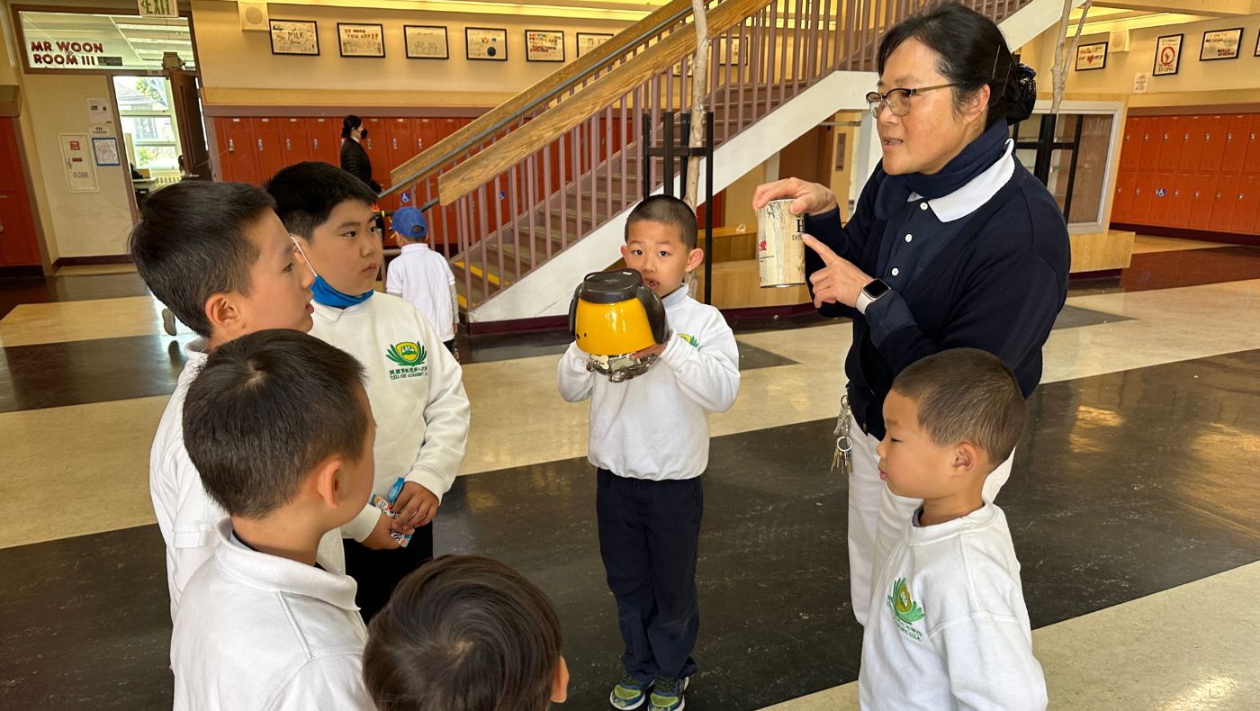 Luo Xueying, a volunteer at San Francisco Humanities School, introduces bamboo tubes of love to students.