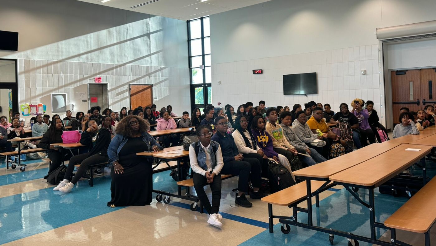 The donation ceremony was held in the school cafeteria, which was full of students.