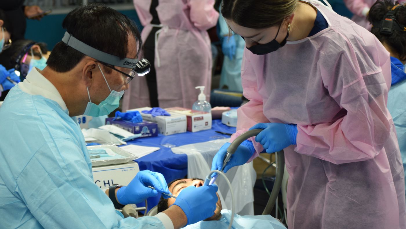 Dentist and assistant examine patient's teeth.