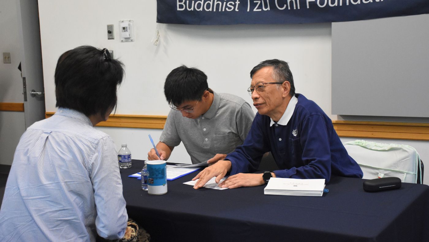 慈濟華府分會執行長季正杭（右一）在發放中聆聽災民訴說他們的故事和心聲，及時給予膚慰。攝影／蔡蕙菁