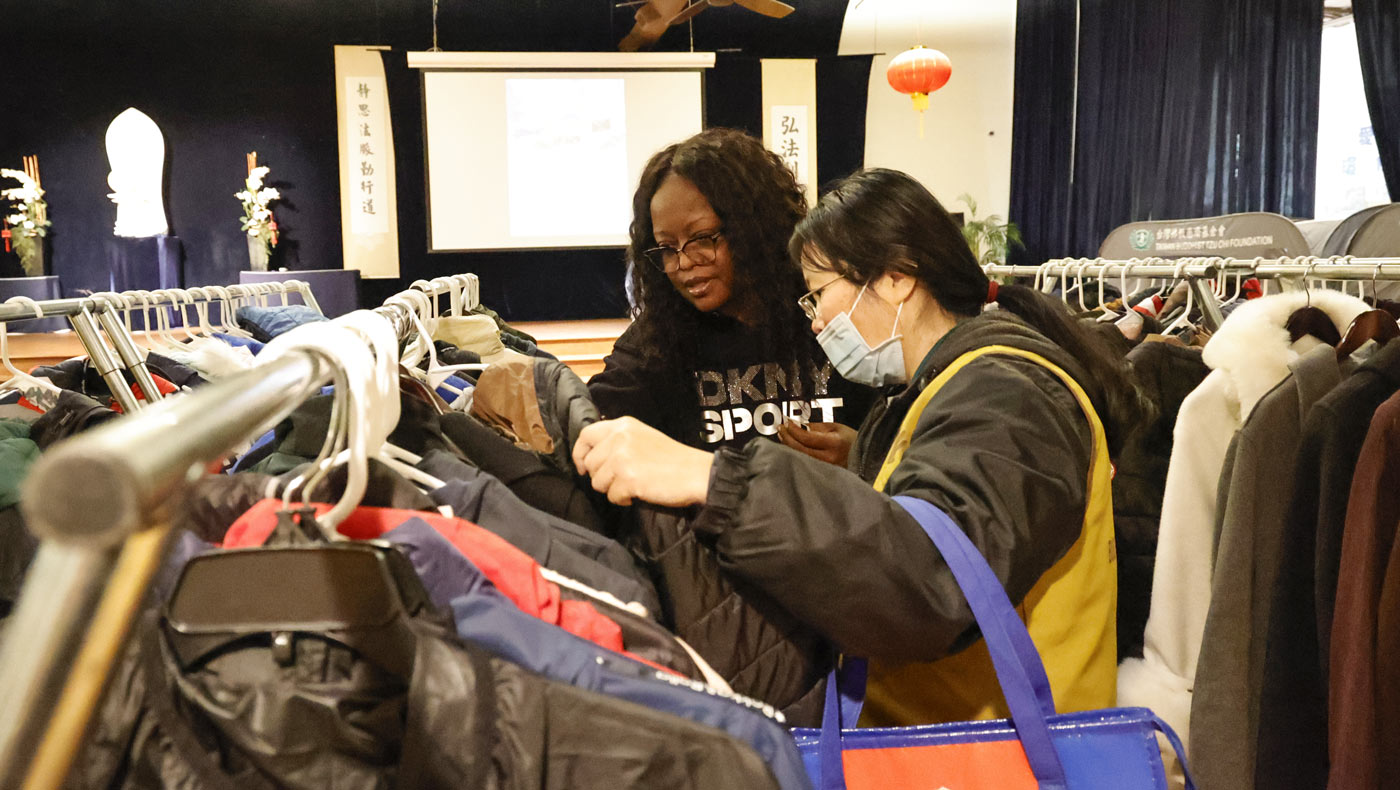 Assisted by a Tzu Chi community volunteer, Johnetta Turner picks what she needs from rows of donated clothes. Photo/Shuli Lo