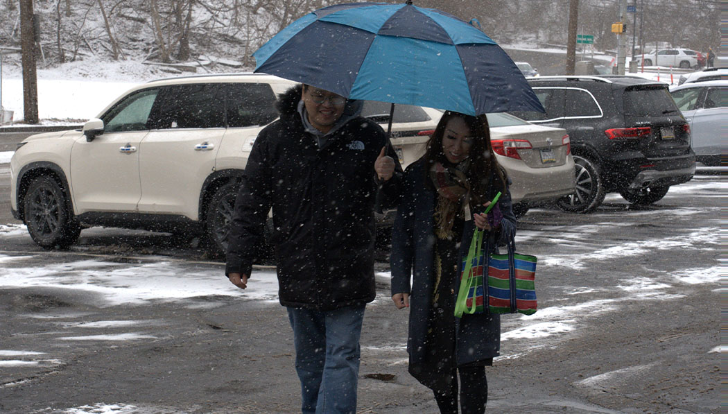 外面下著大雪，交通組志工劉政德（圖左）溫馨的為來參加活動的會眾撐起擋雪的傘。攝影／李東昌
