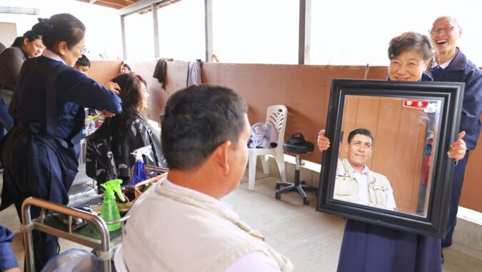 Volunteers provide free haircutting services to the teachers, students, and staff of the Classroom of Hope, and volunteer Hsiuyun Tsai holds up a mirror to show a guest their finished haircut. Photo/Shuli Lo