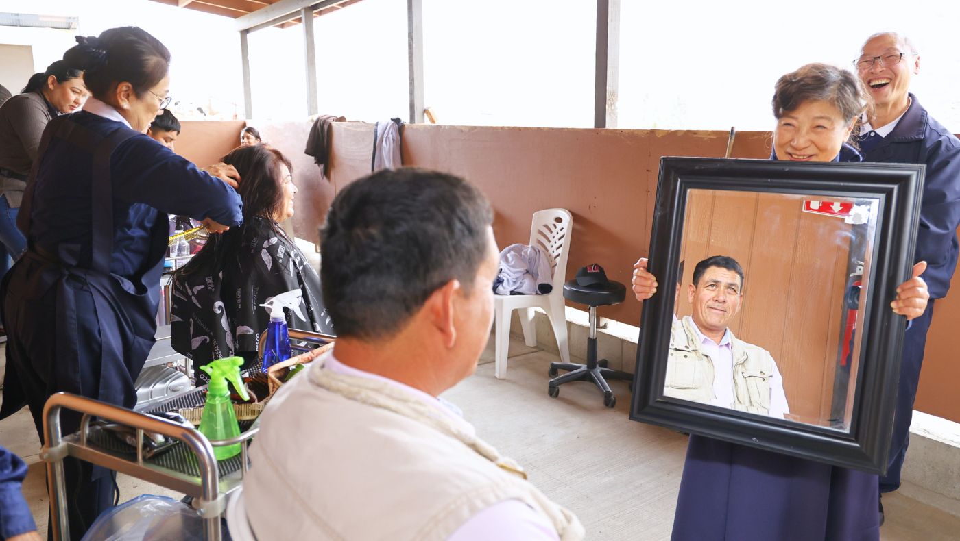 Volunteers provide free haircutting services to the teachers, students, and staff of the Classroom of Hope, and volunteer Hsiuyun Tsai holds up a mirror to show a guest their finished haircut. Photo/Shuli Lo