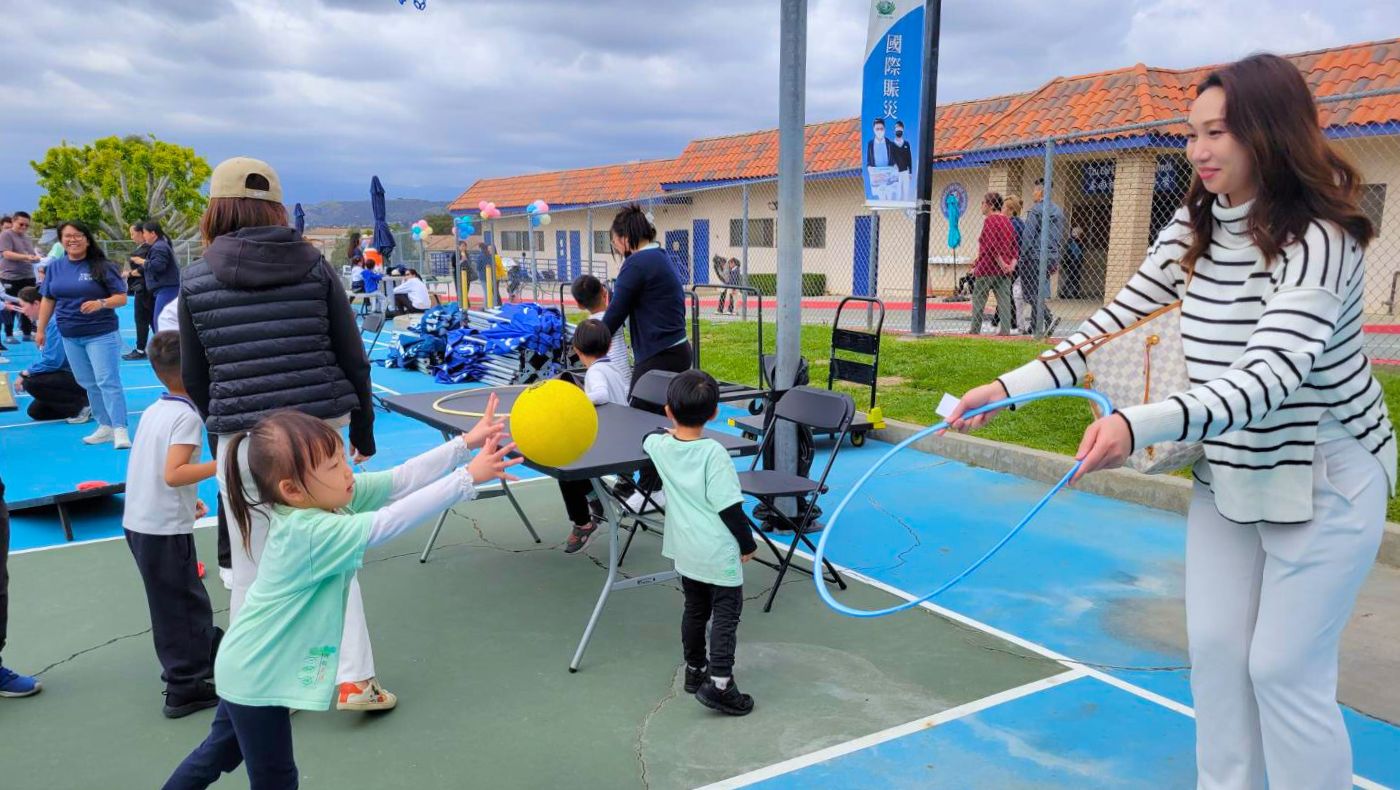 學生與家長玩傳球過呼拉圈遊戲，這是一項訓練手眼協調與親子互動的趣味活動。攝影／蔡怡暄
