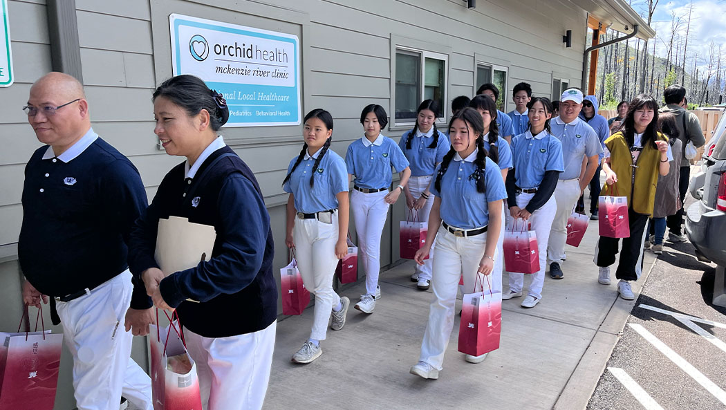 Los voluntarios del Grupo Juvenil Tzu Chi caminan con una cálida sonrisa mientras llevan los paquetes de ayuda que prepararon para los bomberos del Distrito Rural de Protección contra Incendios de Upper McKenzie. Foto/Minru Chao