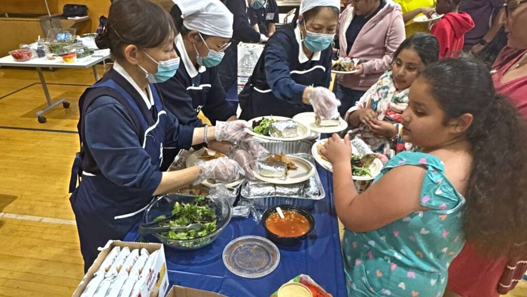 Voluntarios de Tzu Chi sirviendo la comida preparada para los asistentes. Foto/Pingyao Lee