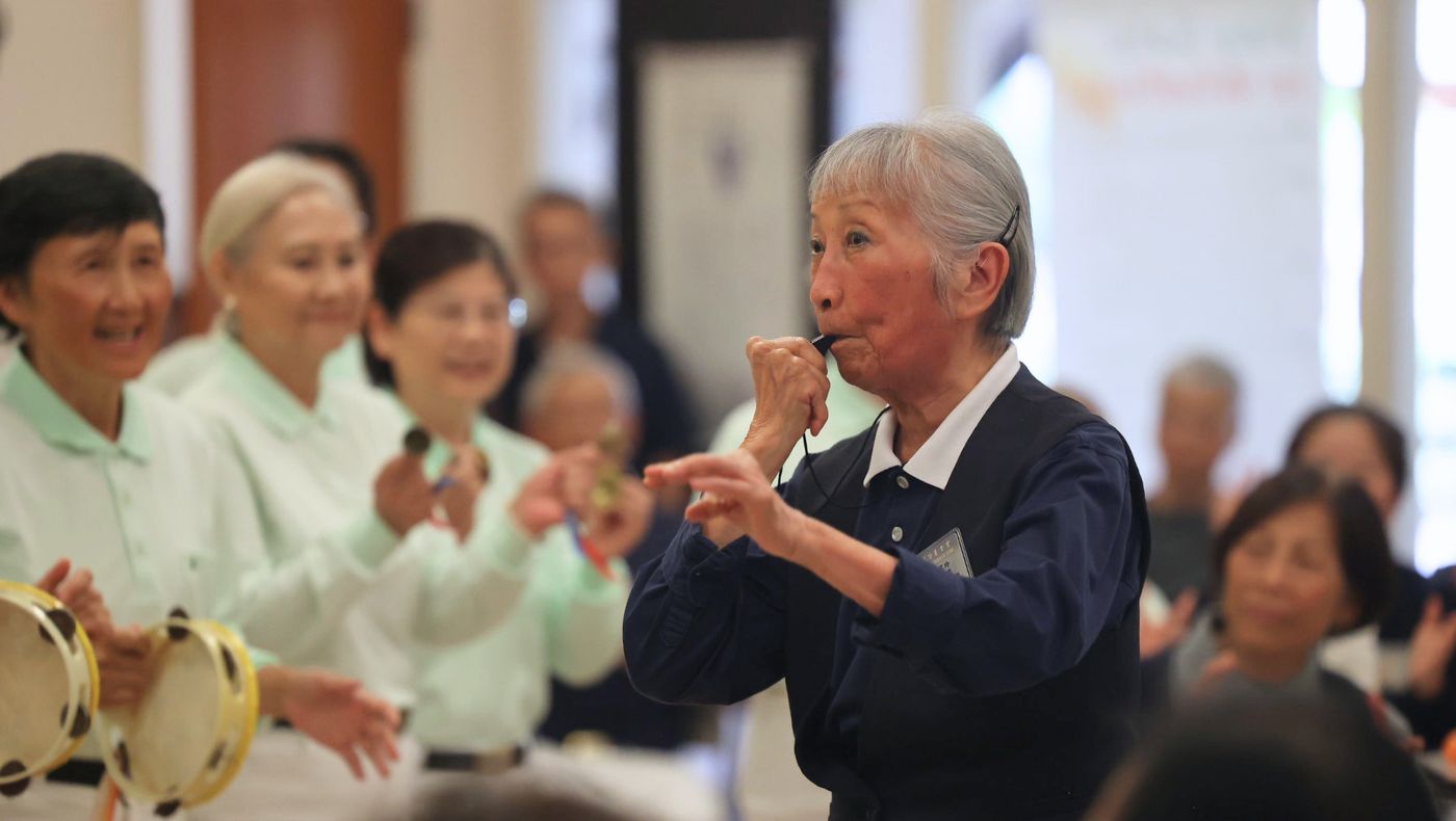 88歲的陳雪玲精神奕奕地吹著哨子，帶領團員表演《桂河大橋》，展現長者的活力與喜悅。攝影／呂宛潔