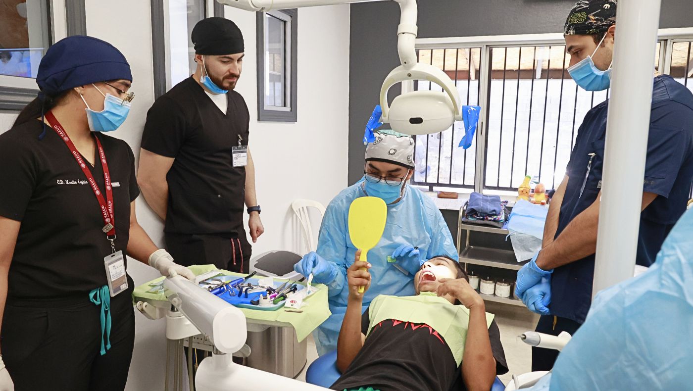 Un paciente examina sus dientes en un espejo tras el tratamiento, mientras el dentista repasa el procedimiento realizado. Foto/Shuli Lo