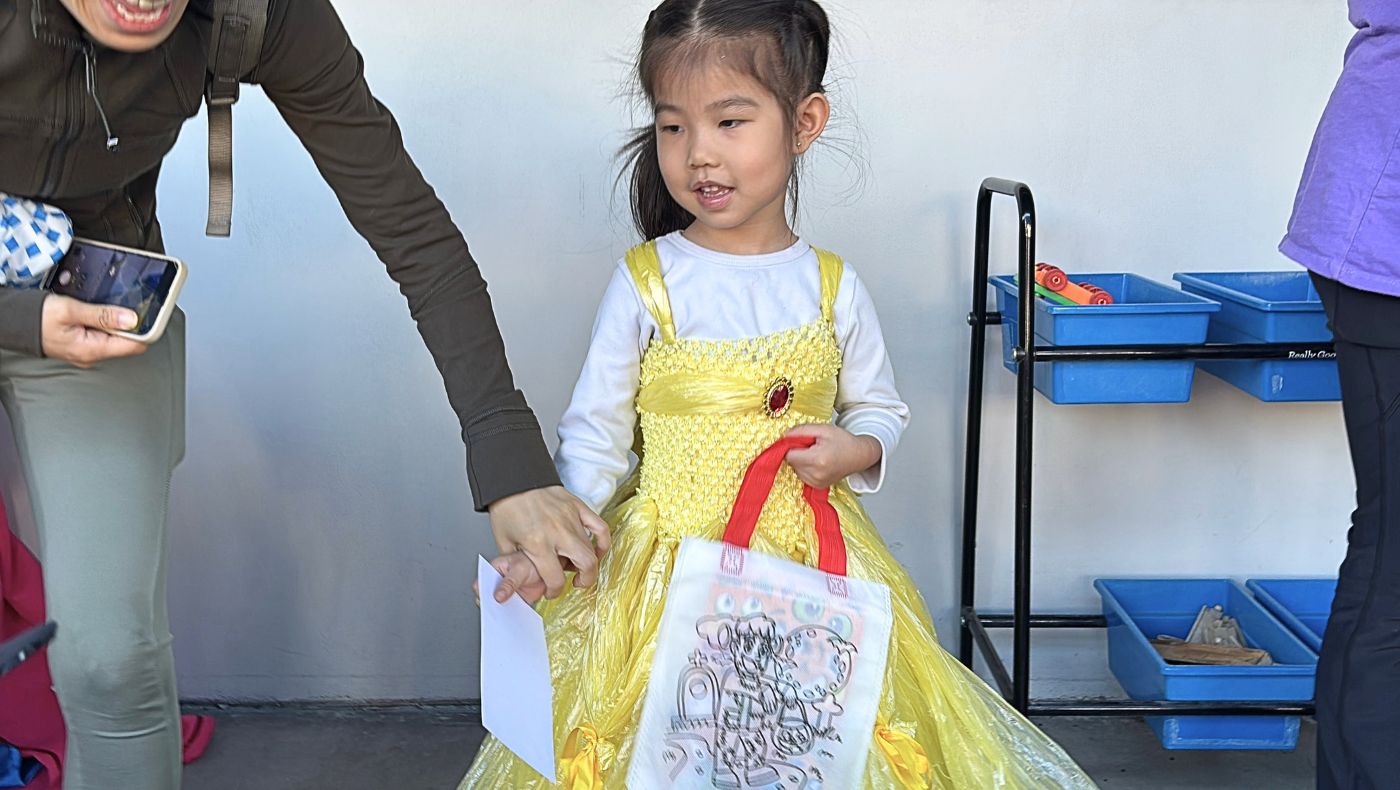 A little girl, dressed in a princess costume made of lightweight plastic, happily participates in Halloween activities. (Photo by Wu Jin)