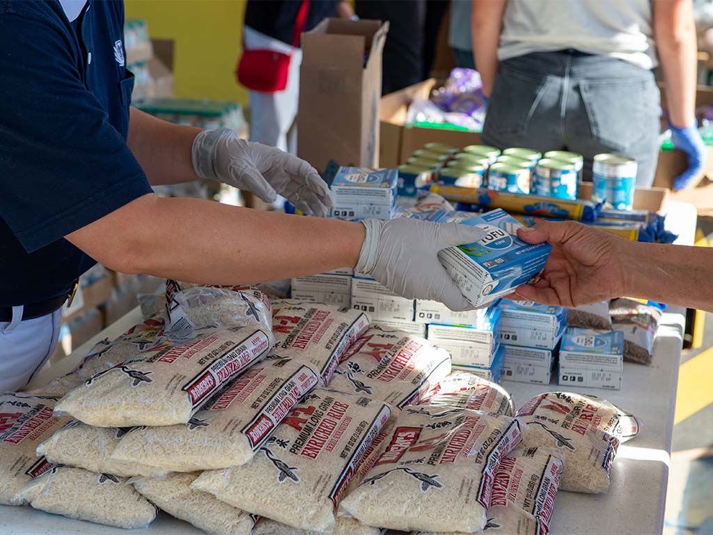 Volunteer handing out tofu and rice at a food distribution event.