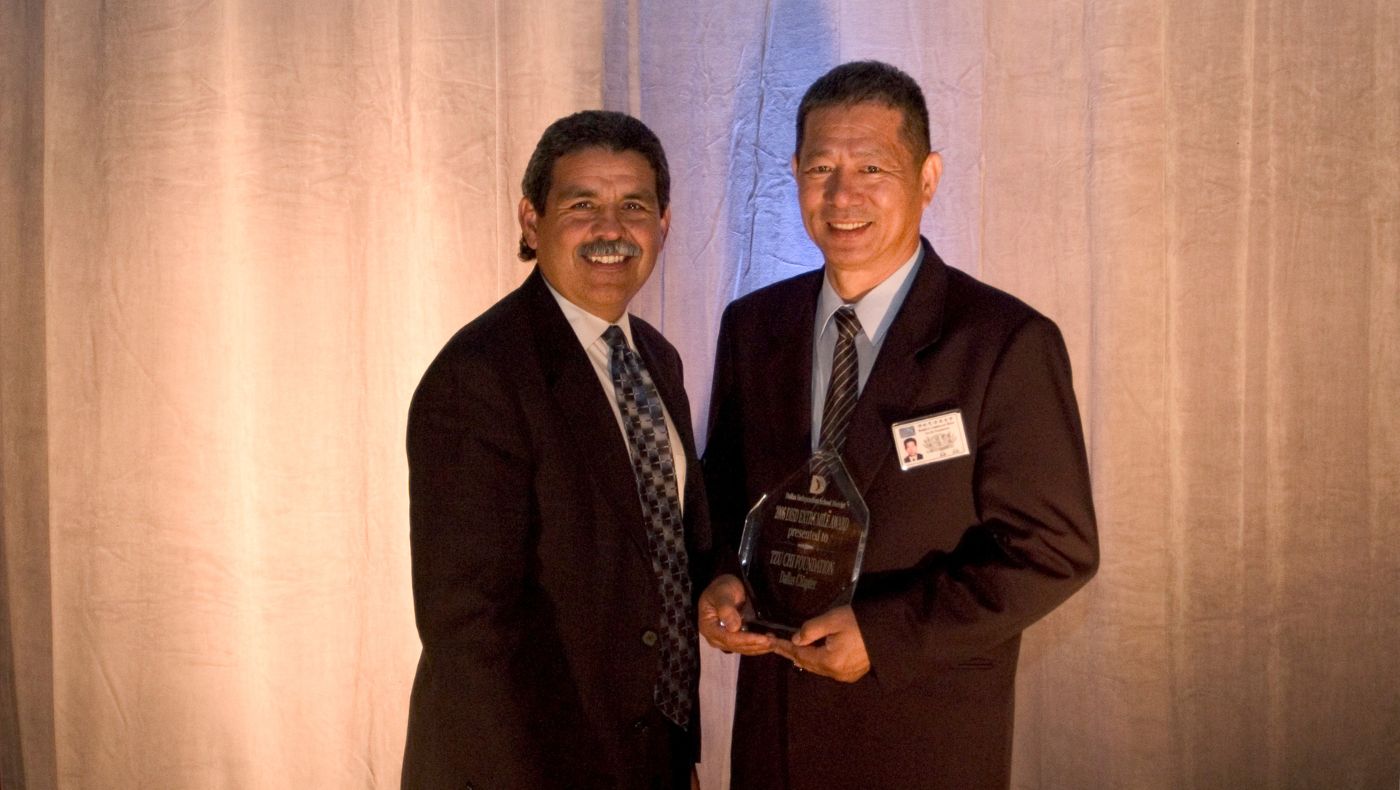 In 2006, the Dallas School District presented an award to the Tzu Chi Dallas branch in recognition of the distribution of uniforms to students from disadvantaged families. Ling Yuanliang (right) accepted the award on behalf of the school. (Photo credit: Wu Meihua)