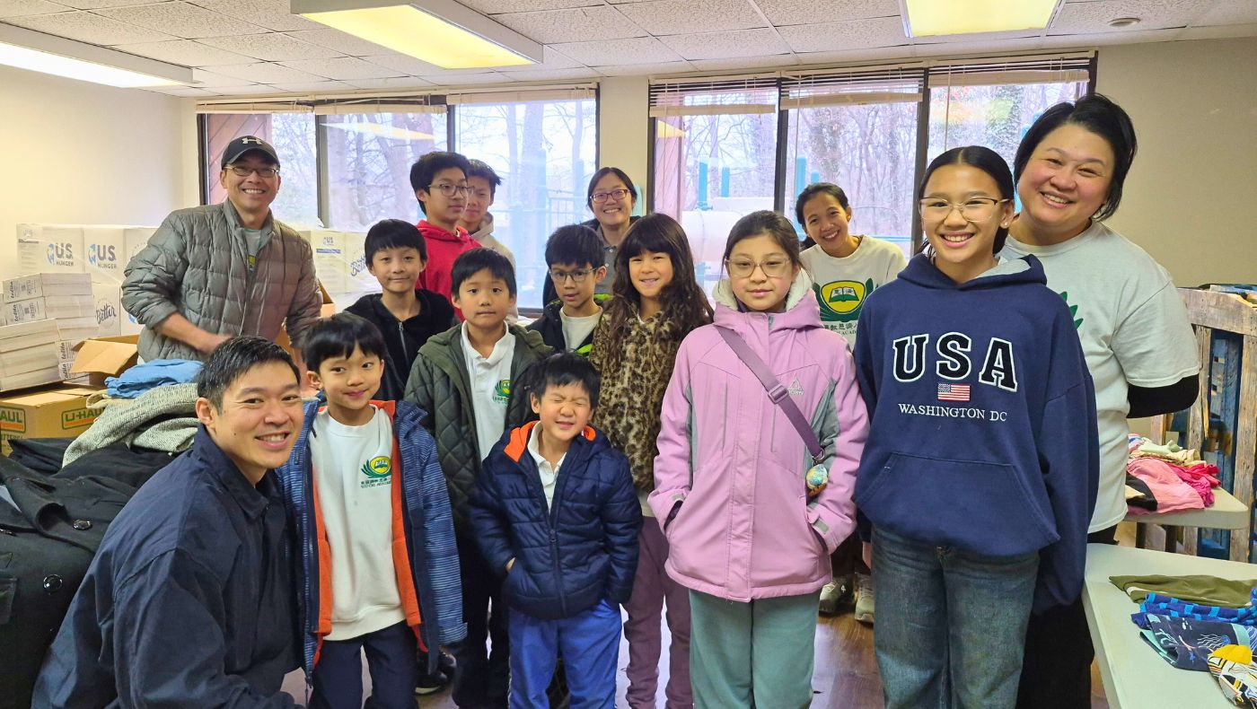 Principal Liu Biwei of the Washington Humanities School poses for a photo with teachers and students who participated in the winter clothing donation drive. Photo by Cai Huijing