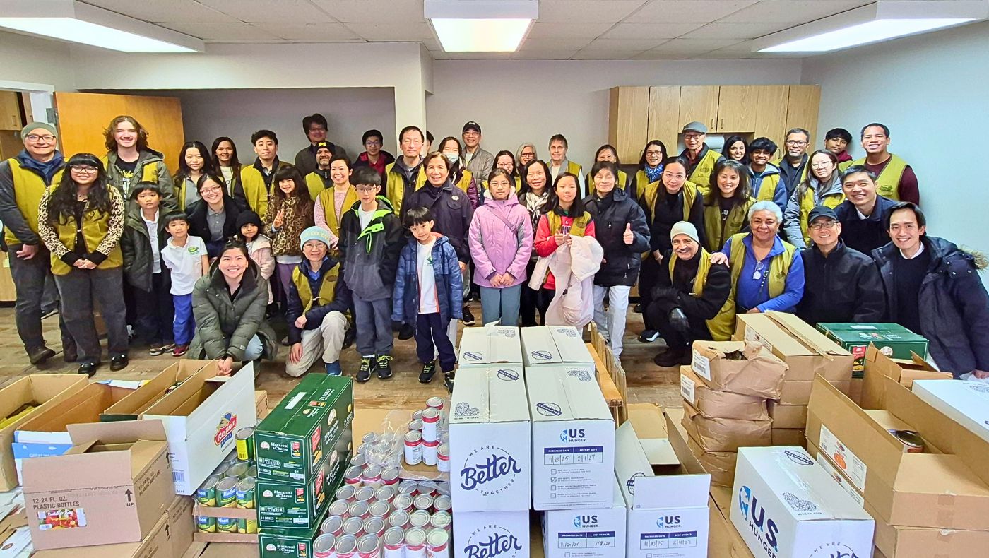 Students and teachers from the Tzu Chi Humanistic School in Washington, D.C., who participated in the winter clothing donation drive, posed for a group photo with food distribution volunteers. Photo by Tsai Hui-ching