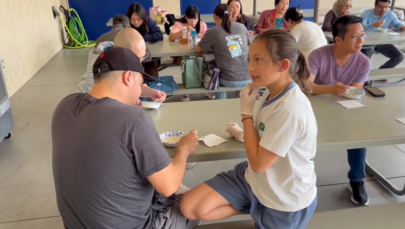 學生主動向家長介紹菜色與料理過程，從服務中學習自信與人際互動。圖片來源／視頻截圖